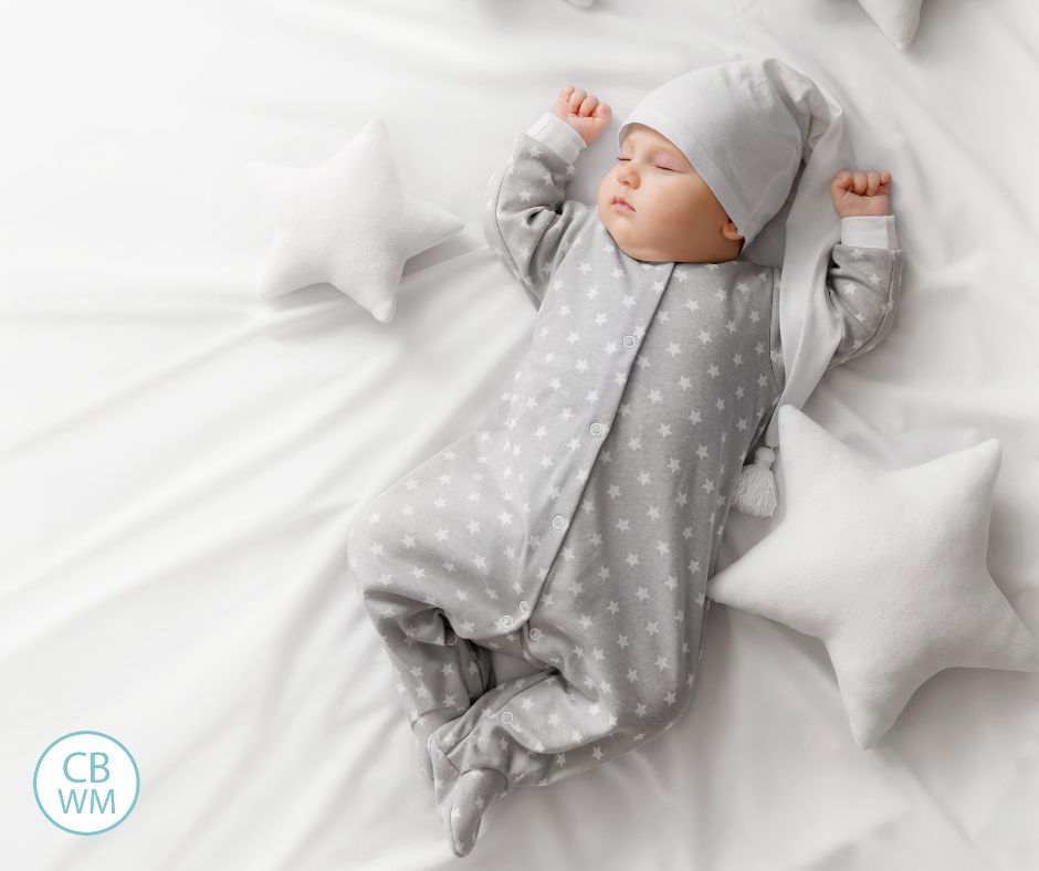 Baby sleeping in the crib at night wearing gray pajamas