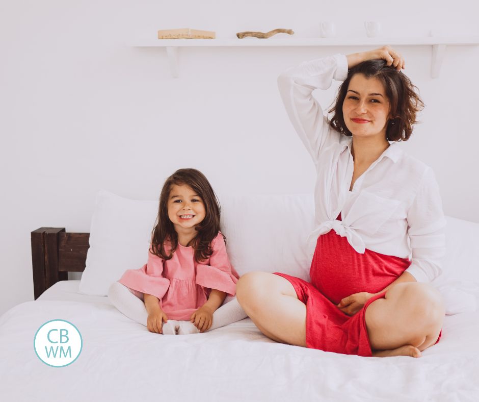 Pregnant mom with toddler sitting on a bed