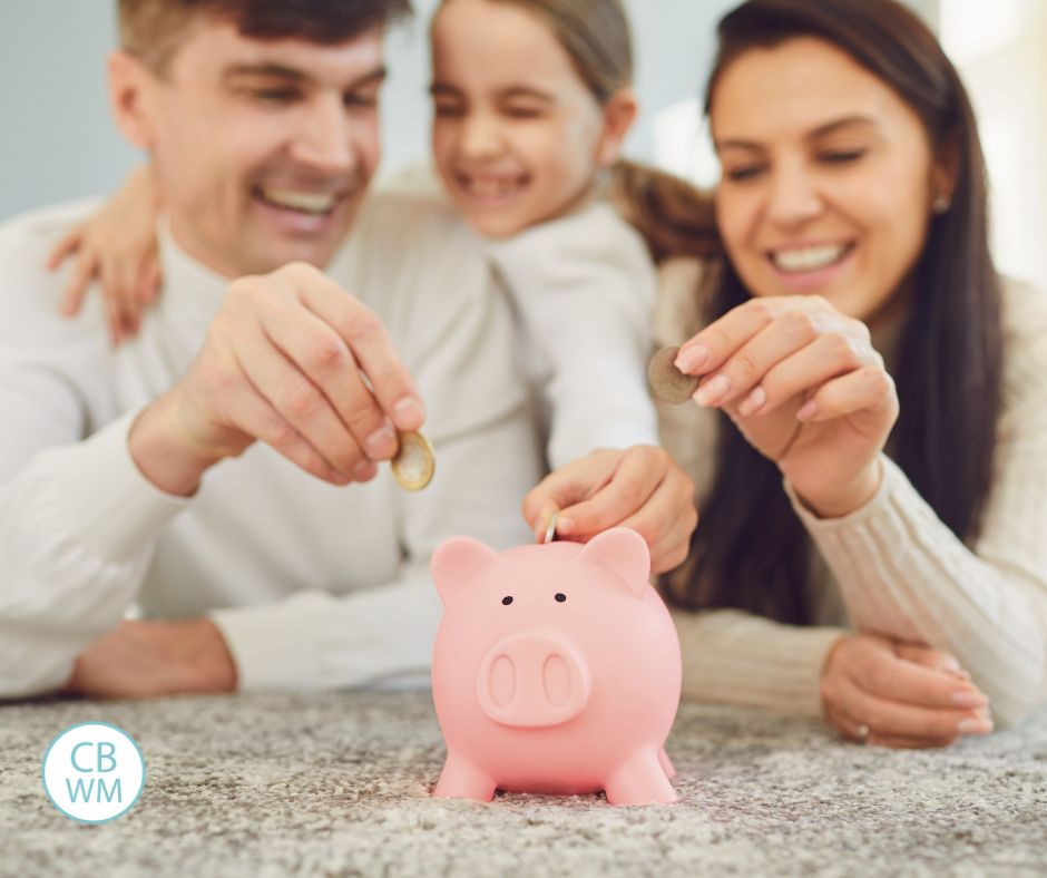 2 parents and their child putting coins in a pink piggy bank