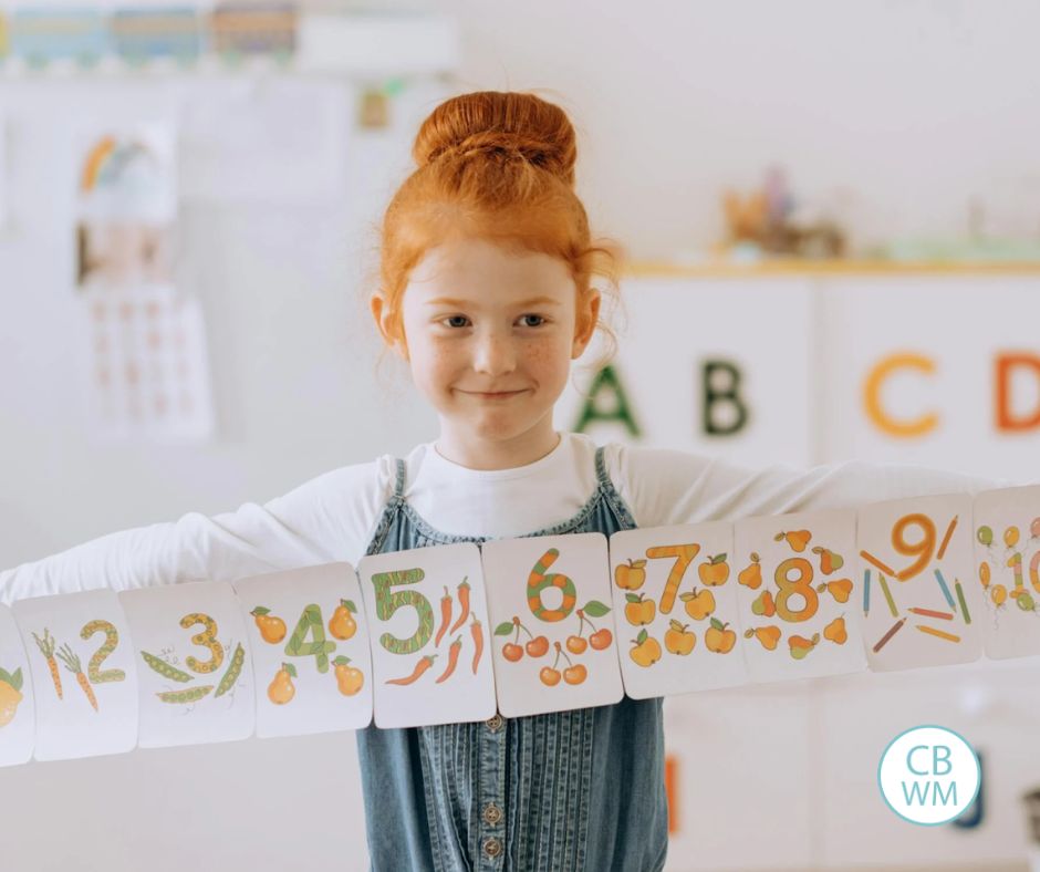 Child holding papers with numbers on them 1-10