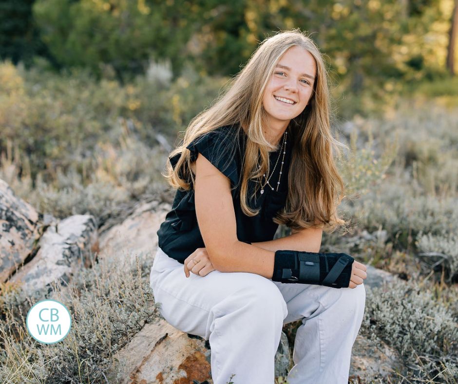 McKenna posing for a photo. She is outside sitting on a rock