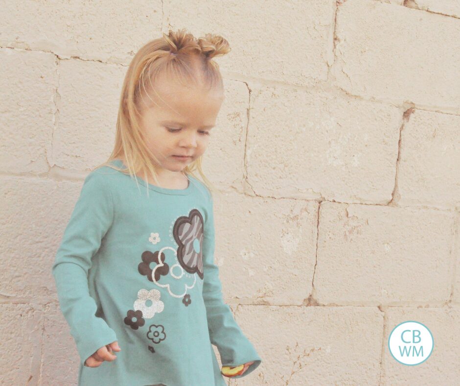 Brinley standing against a cinderblock wall looking at the ground