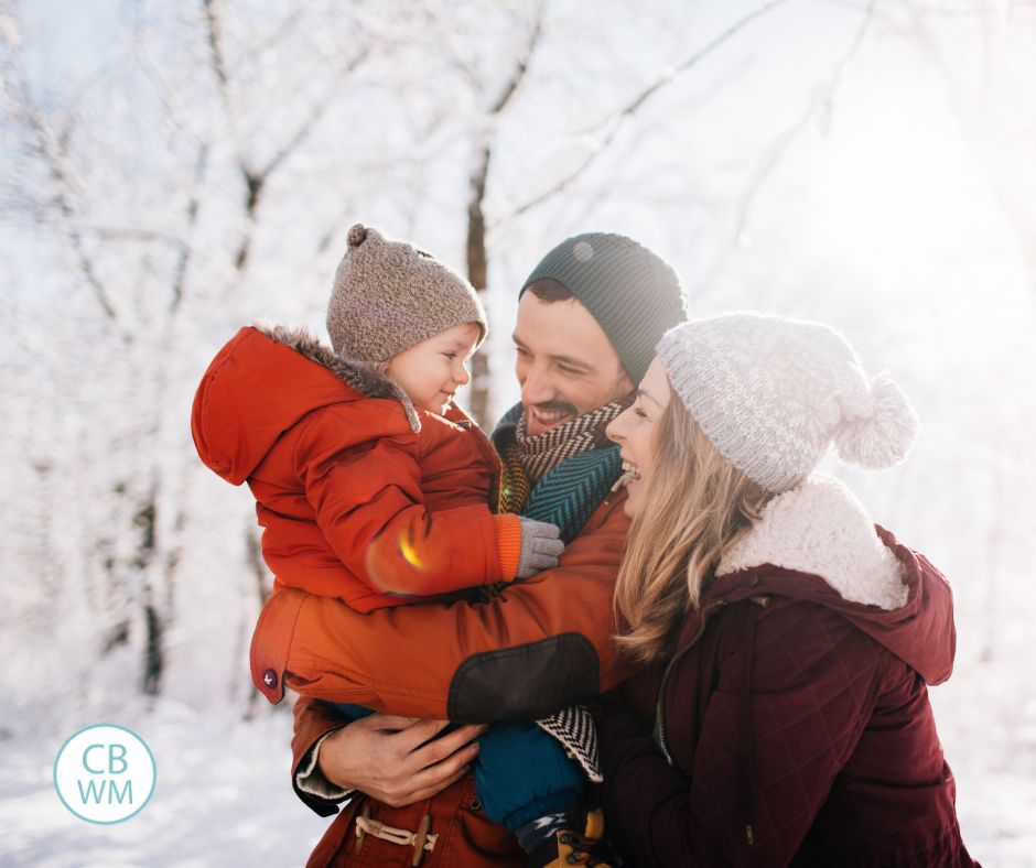 Family of 3 outside in the winter looking at each other and smiling