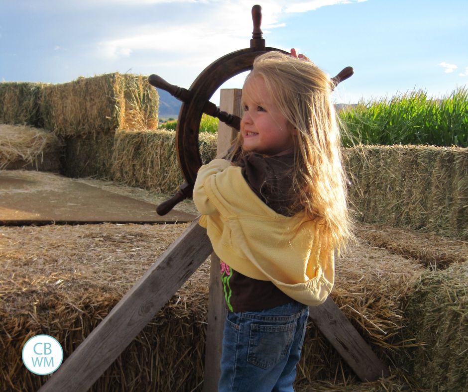Kaitlyn standing at a pirate ship wheel