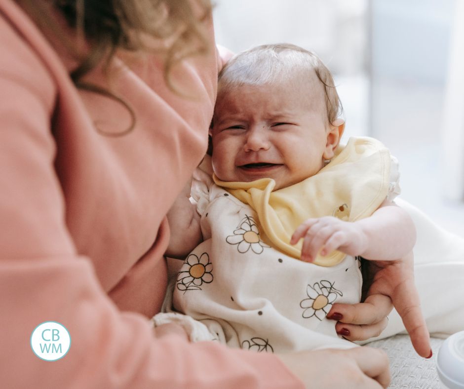 Crying baby sitting in mom's lap