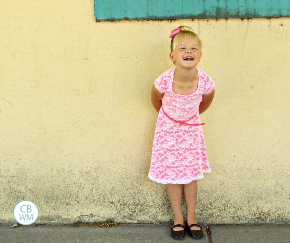 McKenna in a pink dress standing in front of a yellow wall