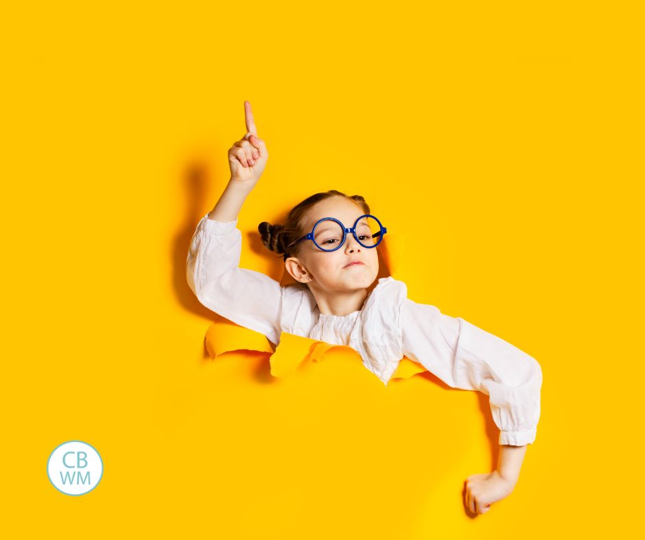 Child wearing glasses breaking through a hole in yellow backdrop