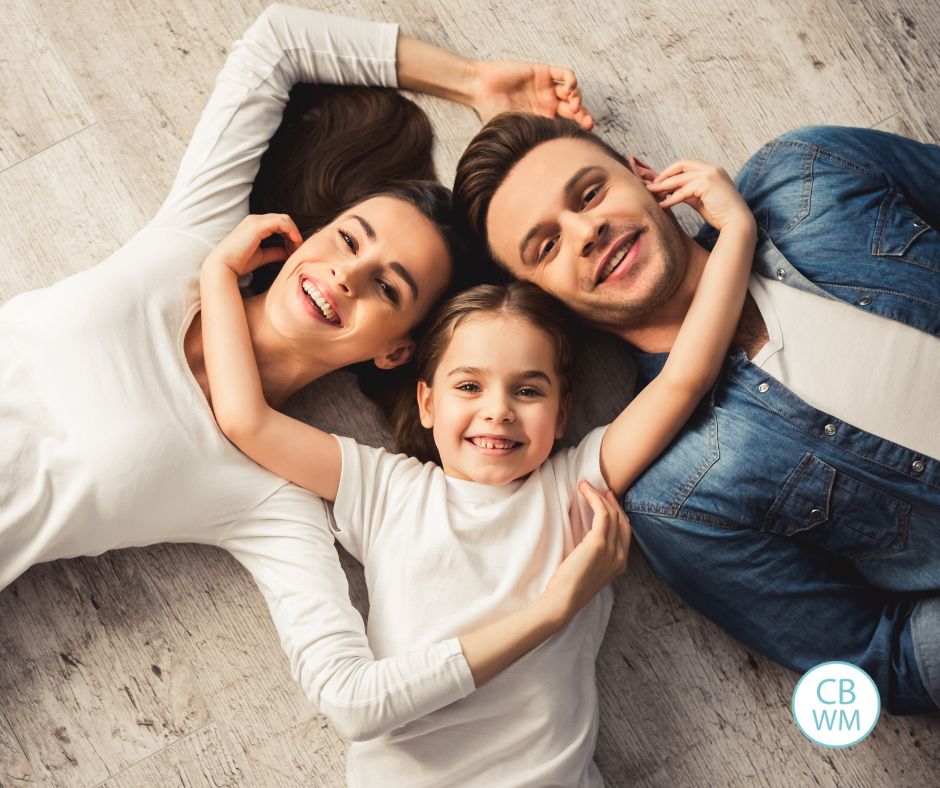 Mom, Dad, and Daughter laying on the floor looking up at the camera
