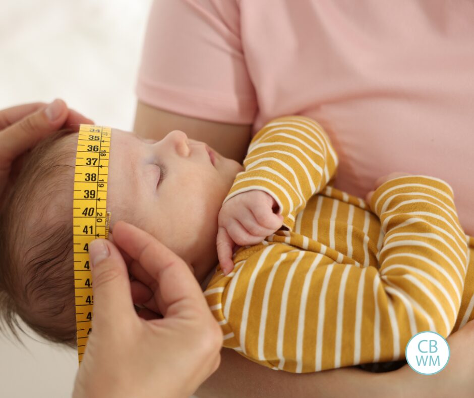 Baby getting her head measured while sleeping in mom's arms