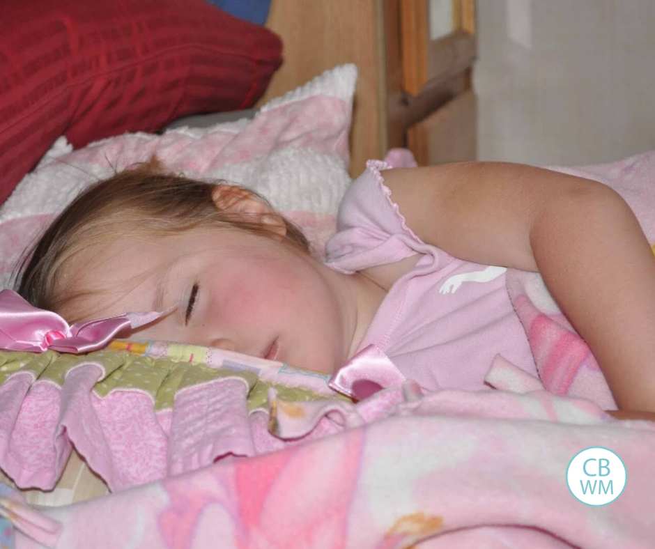 Kaitlyn asleep on a bed with pink blanketes around her