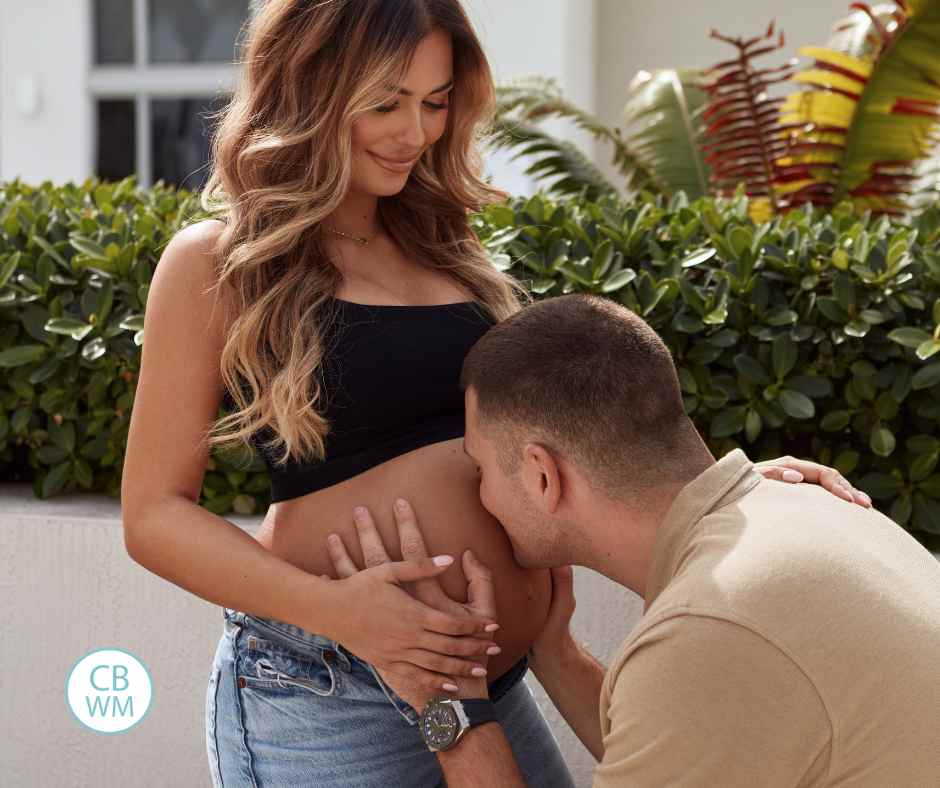 husband kissing his wife's pregnant belly