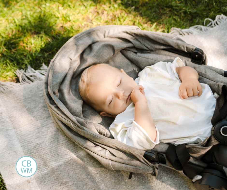 Child sleeping outside in the shade of a tree on the grass