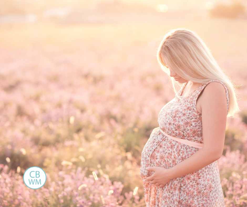 Pregnanty woman wearing a flower dress standing in a field of flowers