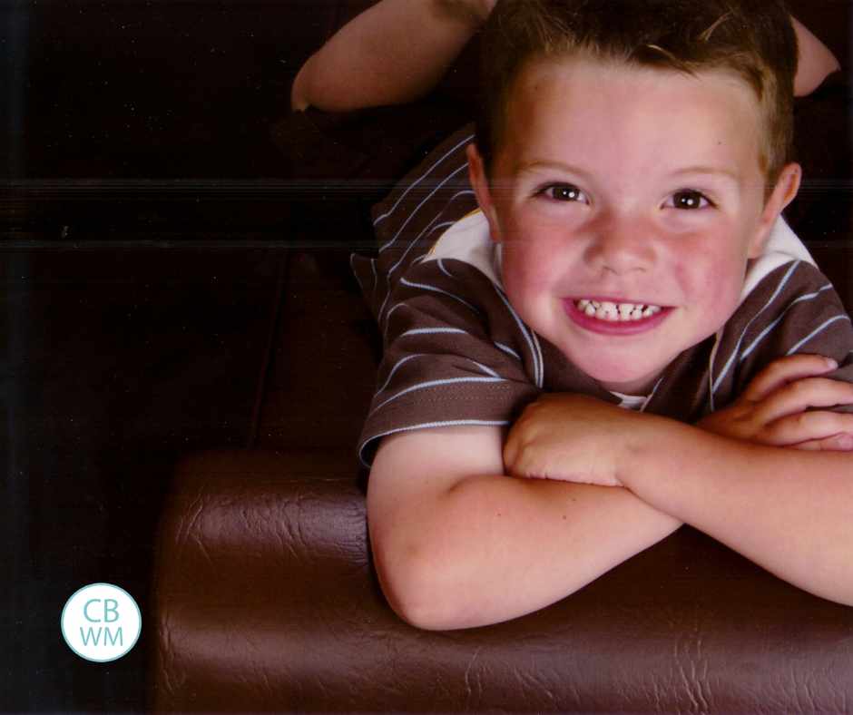 4 year old Brayden on his tummy, with arms folded, smiling at the camera