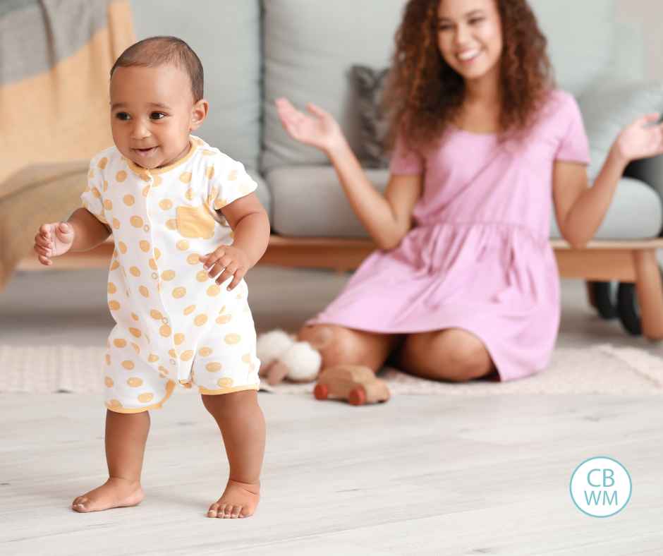 toddler learning to walk with mom excited in the background
