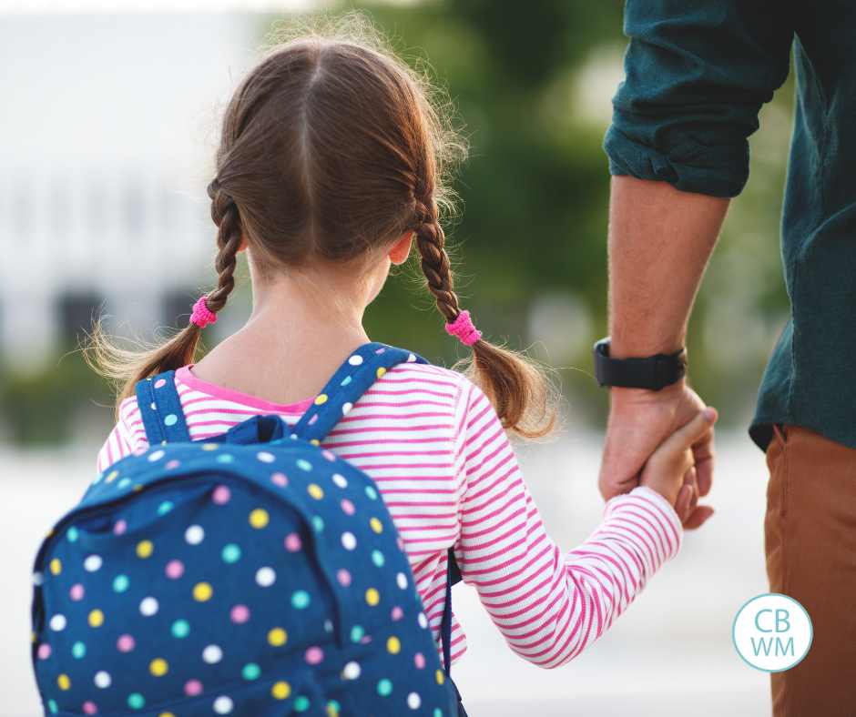 Girl holding her Dad's hand walking to school