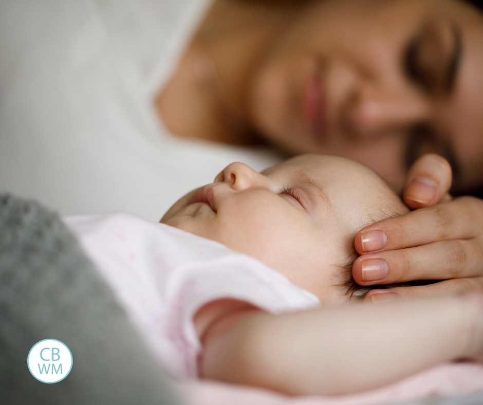 Baby sleeping with mom with hand on baby's head