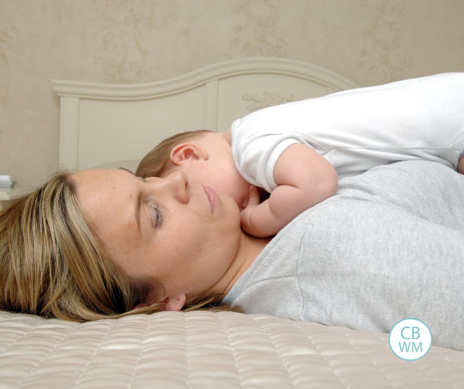 Tired mom laying on the bed with her newborn on her chest