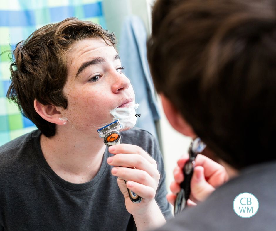 Teenage boy shaving his face